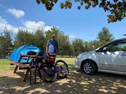 Man stood next to picnic table with bikes in front of a caravan