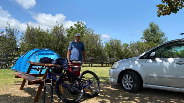 Man stood next to picnic table with bikes in front of a caravan