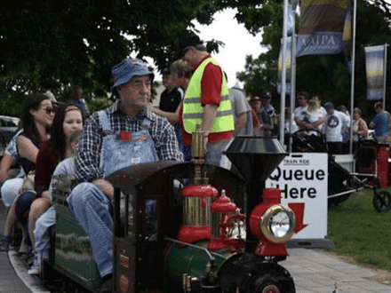 Old miniature train with passengers driven by conductor 