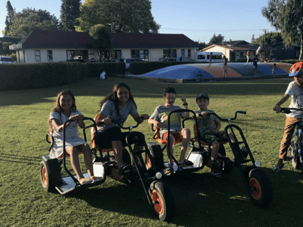 4 children in go-karts on grass 